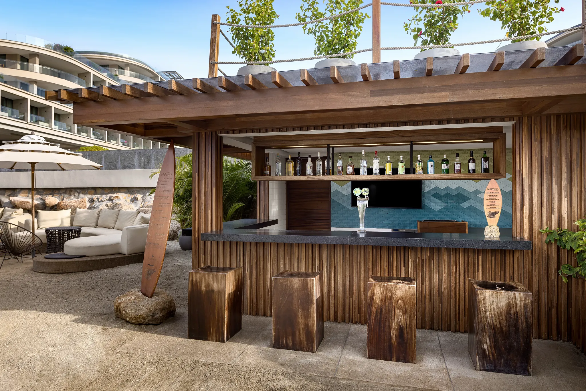 Barracuda Beach Bar at Secrets Bahia Mita Surf & Spa Resort featuring a rustic open-air bar with beach seating, surfboard décor, and tropical cocktails.