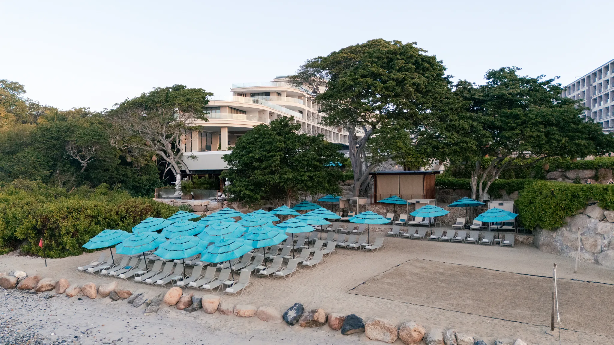 Beach club lounge chairs and umbrellas set along the shore at Secrets Bahia Mita Surf & Spa Resort in Riviera Nayarit.