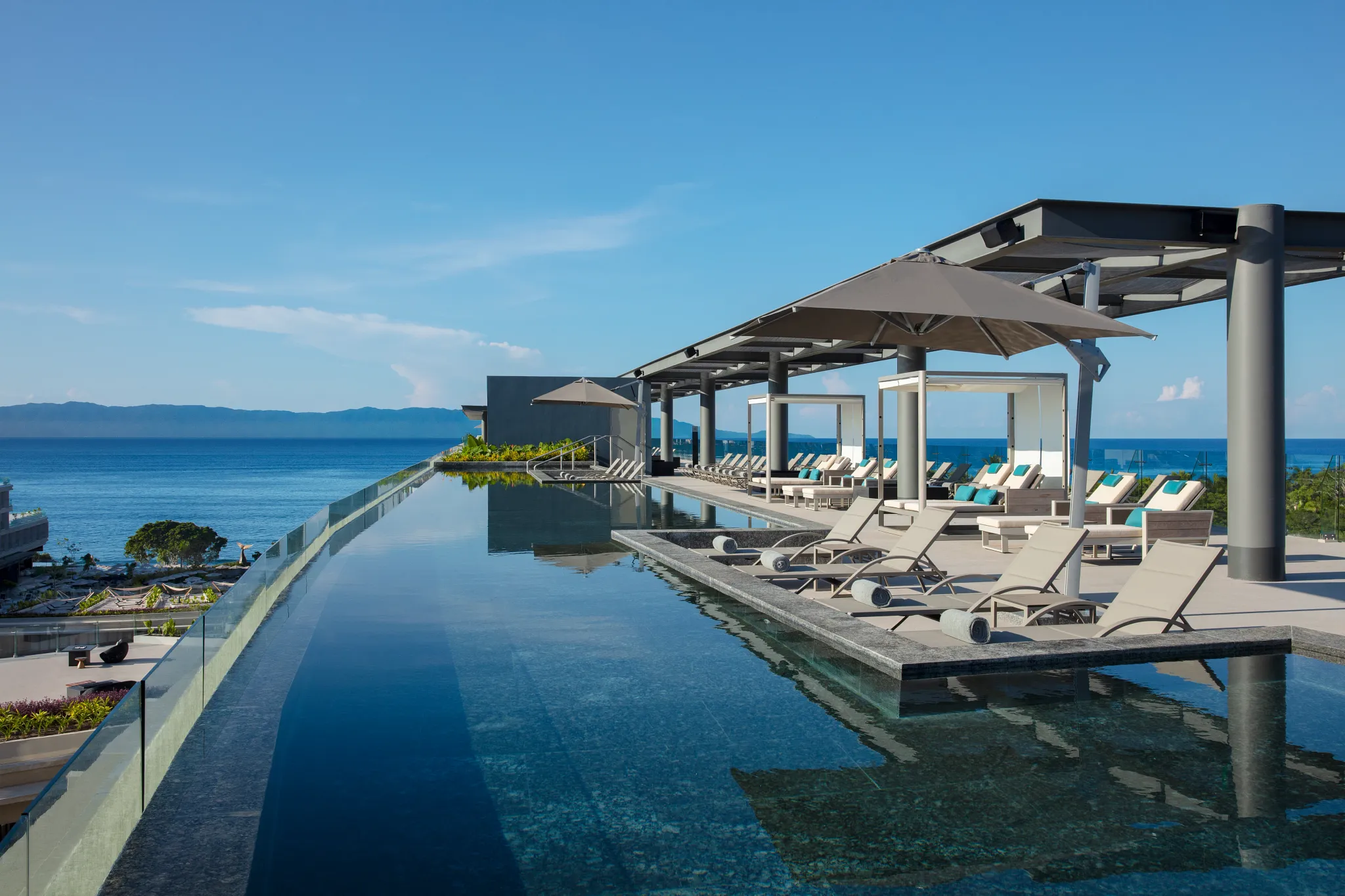 Infinity water deck with loungers and ocean views at Secrets Bahia Mita Surf & Spa Resort.