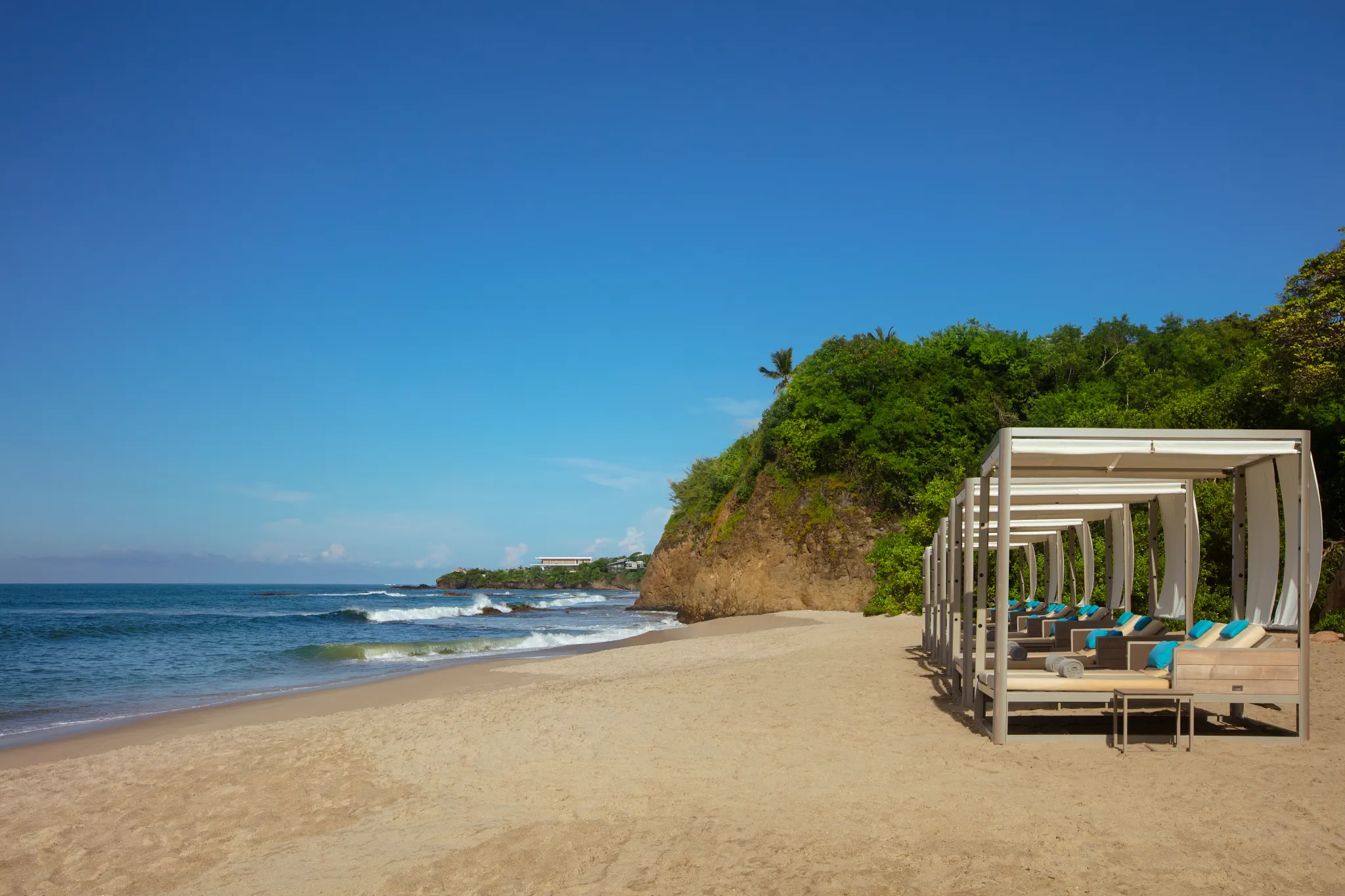 Secluded beach with private cabanas and turquoise water at Secrets Bahia Mita Surf & Spa Resort.