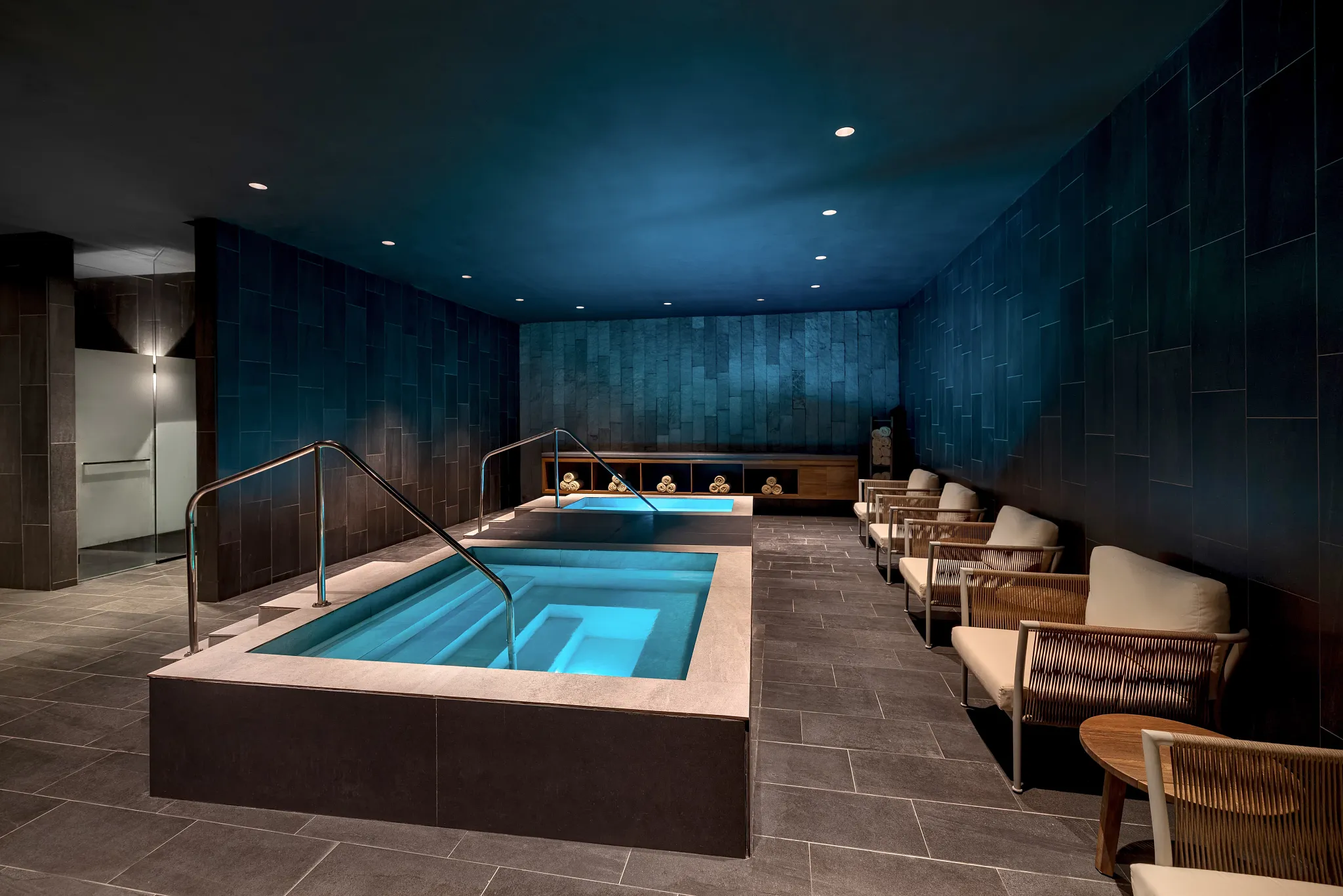 Indoor hydrotherapy pools at Secrets Bahía Mita Surf & Spa Resort featuring calming blue lighting and serene spa seating.