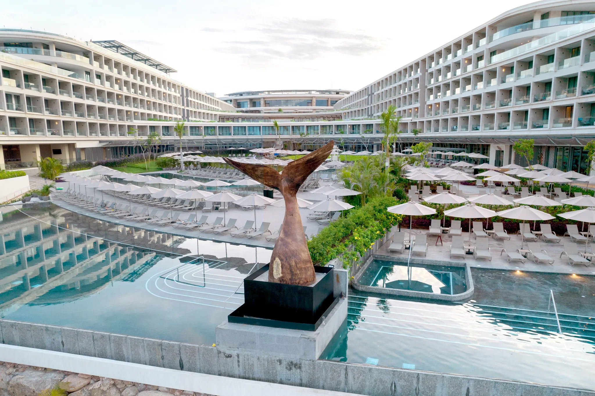 Expansive pool area with lounge chairs and sculptural centerpiece at Secrets Bahia Mita Surf & Spa Resort.