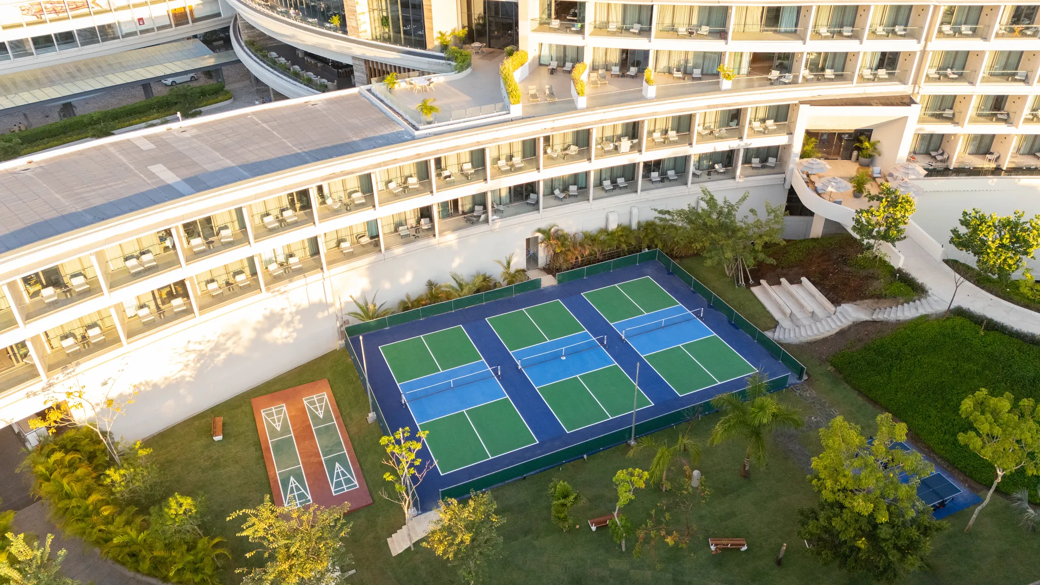 Pickleball courts surrounded by lush gardens at Secrets Bahia Mita Surf & Spa Resort.