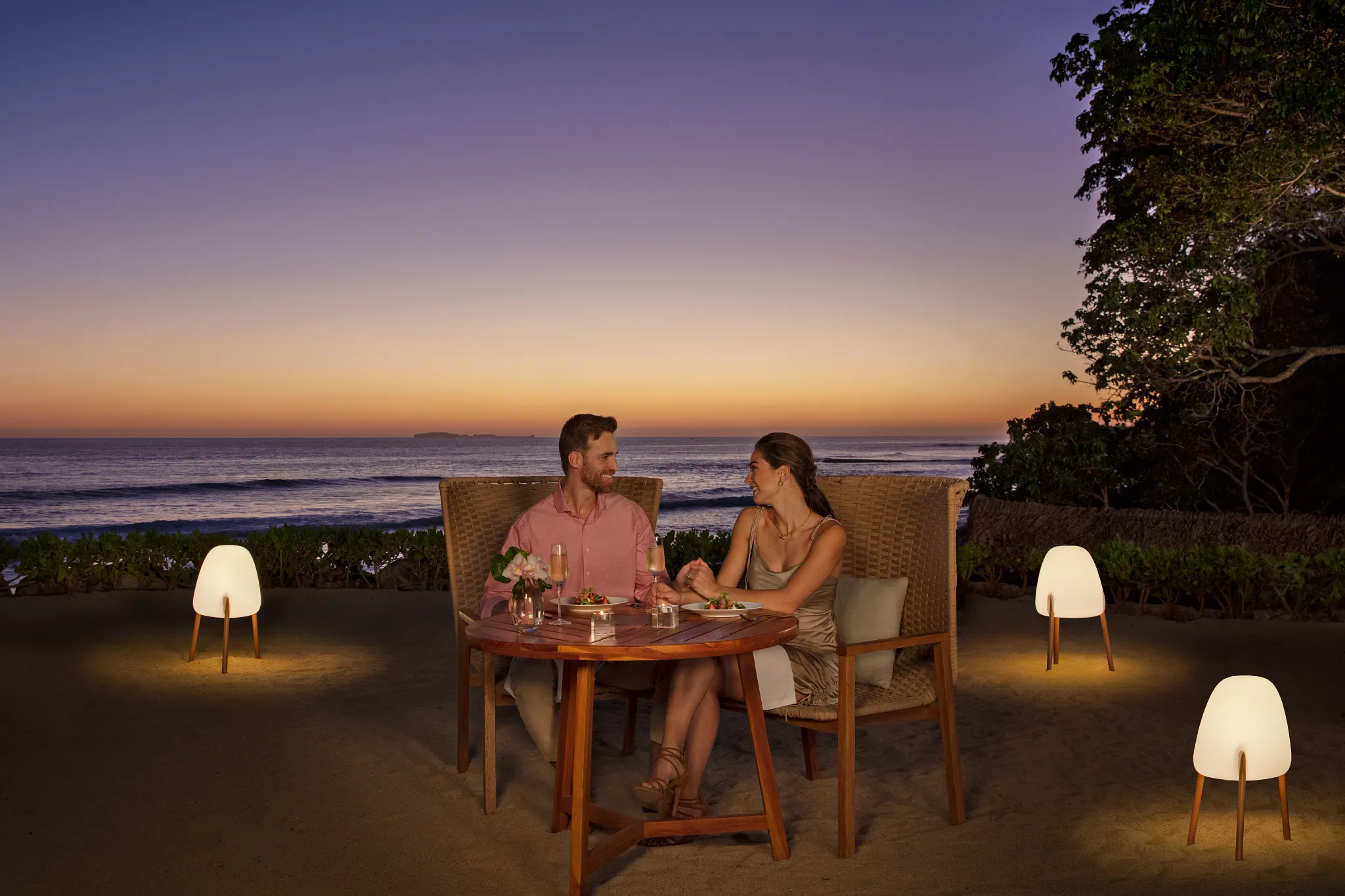 Couple enjoying a private beachfront dinner at sunset at Secrets Bahía Mita Surf & Spa Resort in Riviera Nayarit.