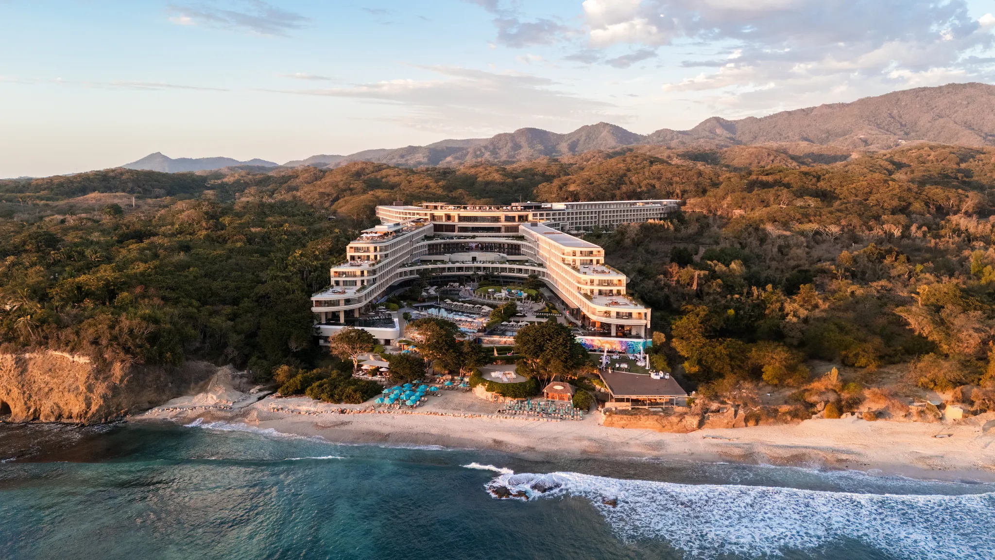 Sunset aerial view of Secrets Bahia Mita Surf & Spa Resort surrounded by jungle and ocean along the Riviera Nayarit.