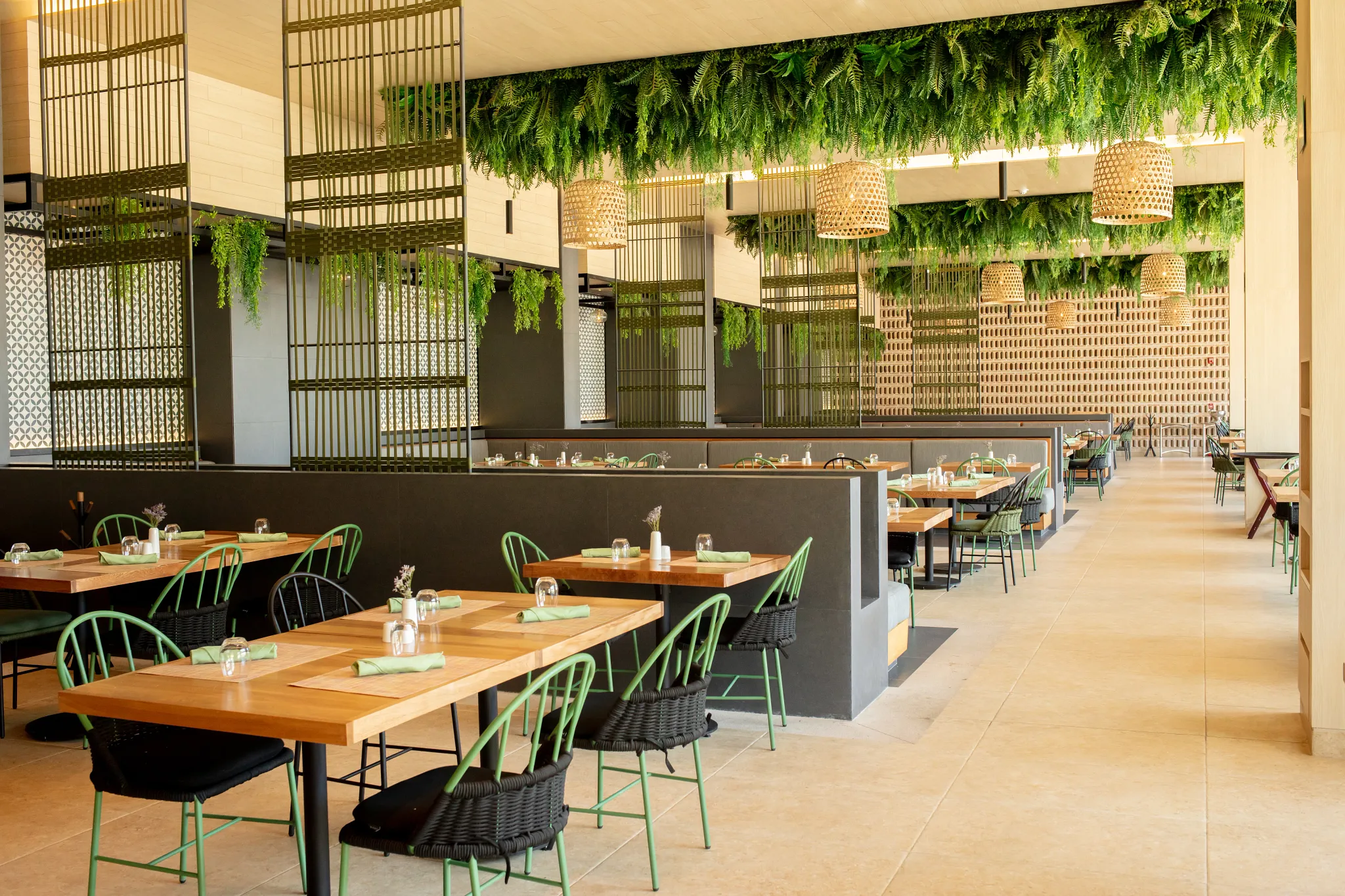 World Café at Secrets Bahia Mita Surf & Spa Resort featuring a modern international buffet restaurant with green accents, hanging greenery, and spacious indoor seating.